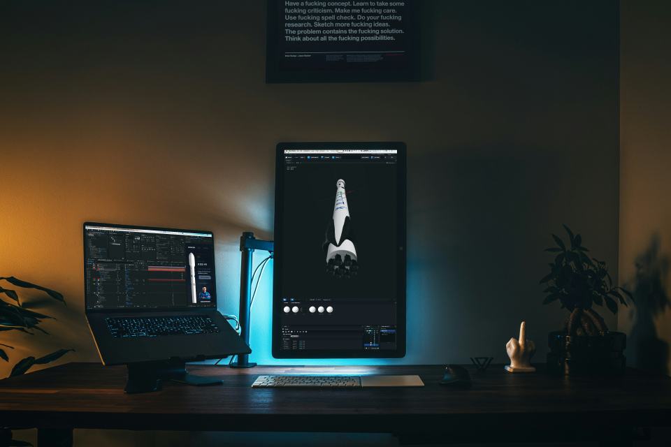 Dark workstation with code and aerospace visualization for advanced technology work.